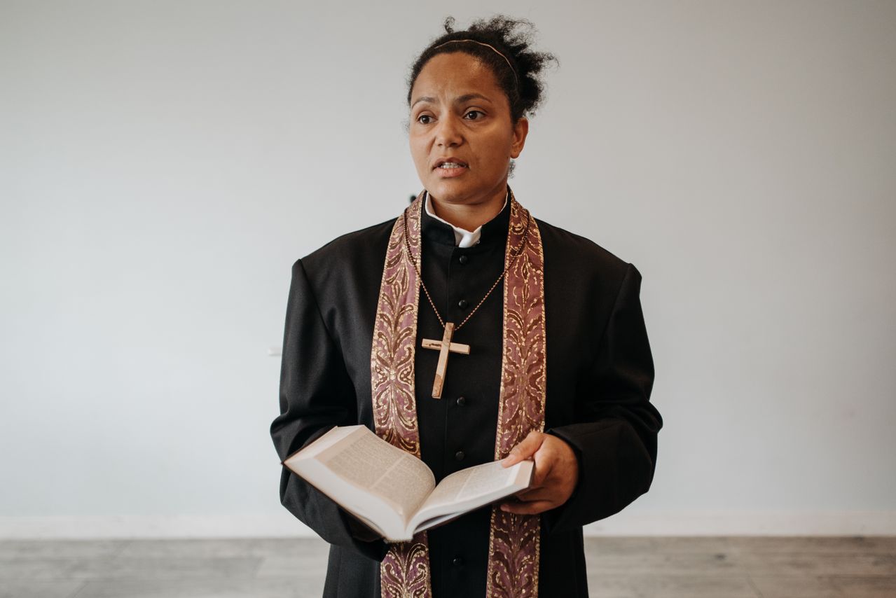 Female clergymember holds a Bible
